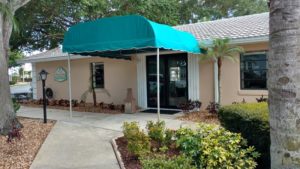 Photo of clubhouse entrance with green awning over it.